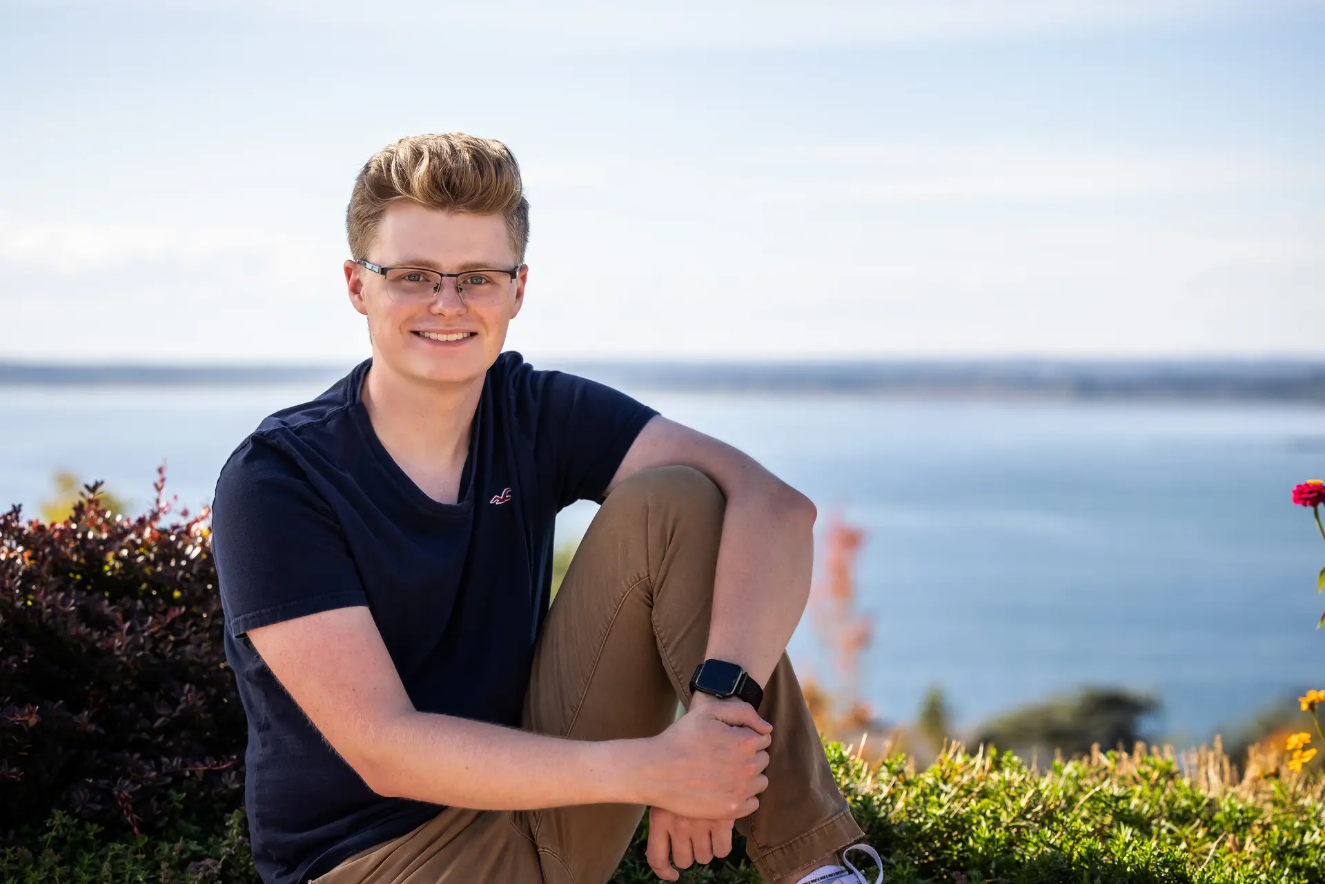 A portrait of me sitting next to an overlook of the ocean.