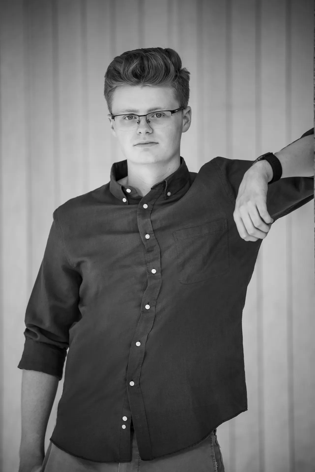 Portrait of Jack leaning against a wall in grayscale.
